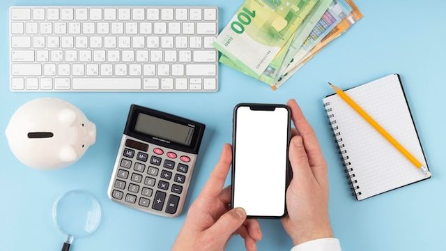 Mão segurando um celular com uma conversa de WhatsApp automatizada ao lado de uma calculadora